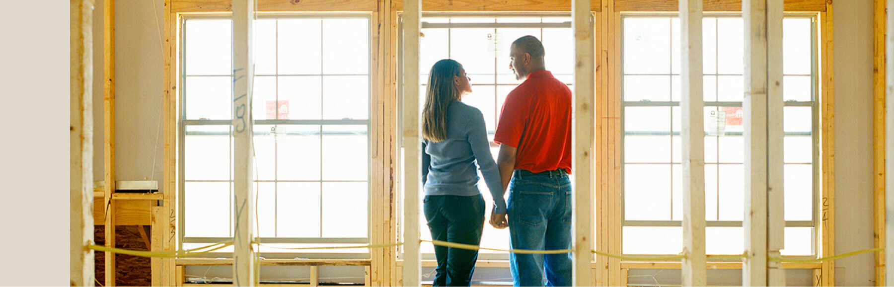 Couple holding hands in home under construction